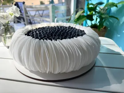 Tarta blanca con volantes de papel de oblea y arándanos por encima