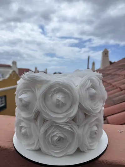 Tarta blanca cubierta de rosas de papel de oblea, en una terraza con tejados canarios